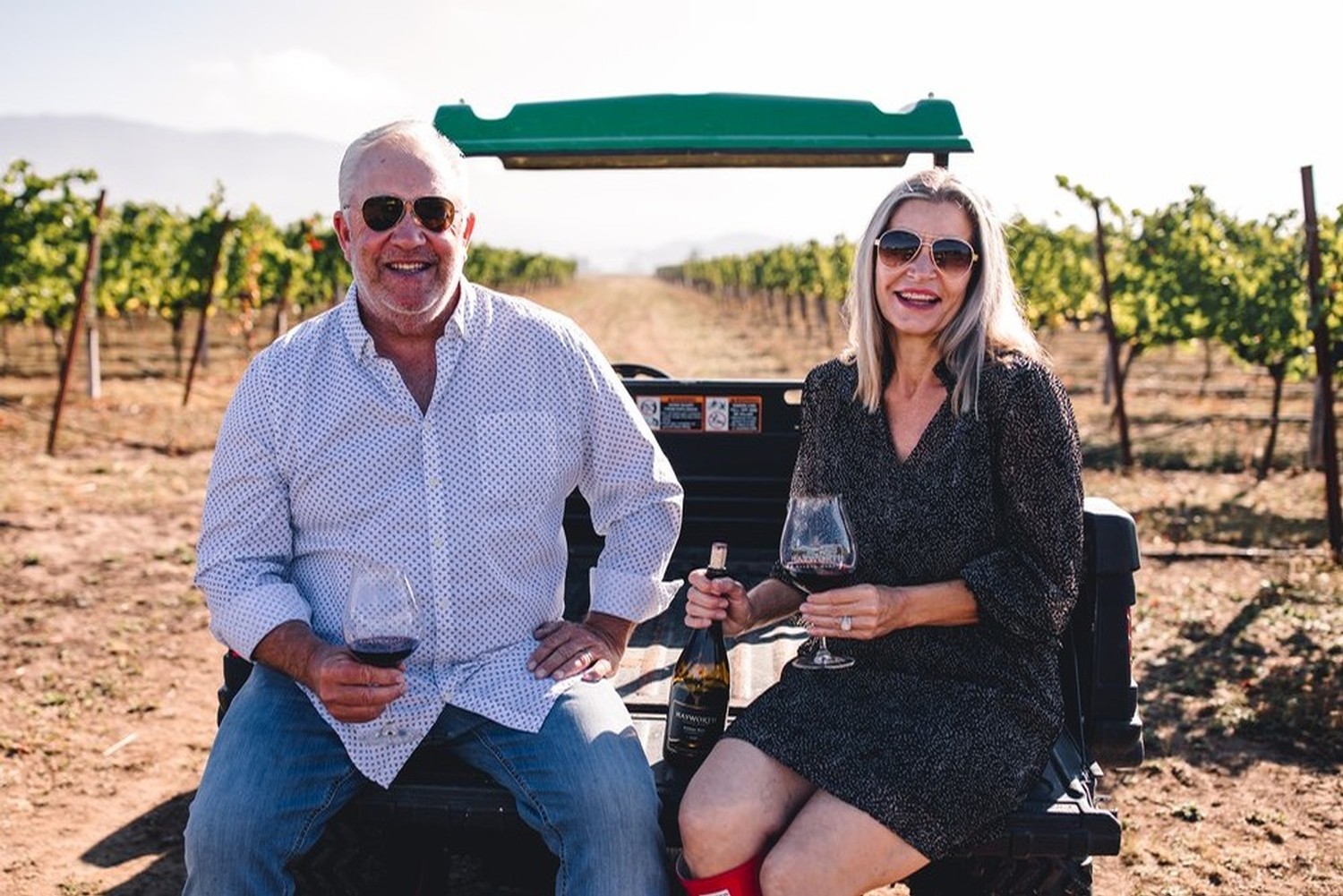 Russ and Keely in the vineyard with wine